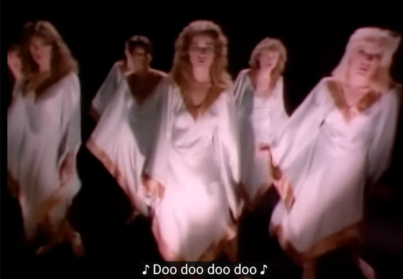 A group of 6 long-haired white women in flowing white gowns in front of a black void. They look like they are in a cult in the 70s and will drink from a poison chalice or stab your heart any minute now. Closed caption reads "Doo doo doo doo".

It's a still frame from the music video "I need a hero" by Bonnie Tyler.